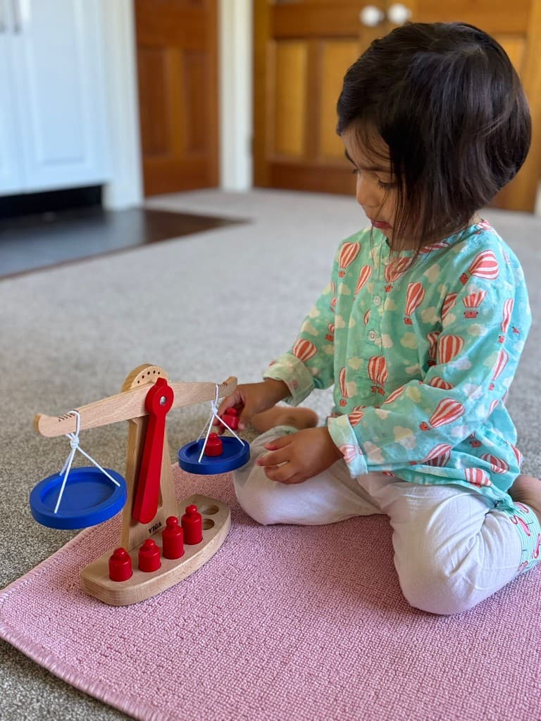 Preschooler exploring balance scale with weights